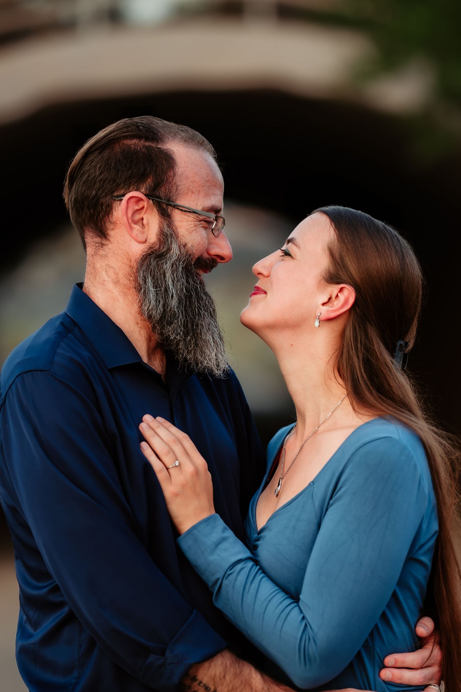 A couple in blue clothing shares a tender moment during an outdoor photo session.