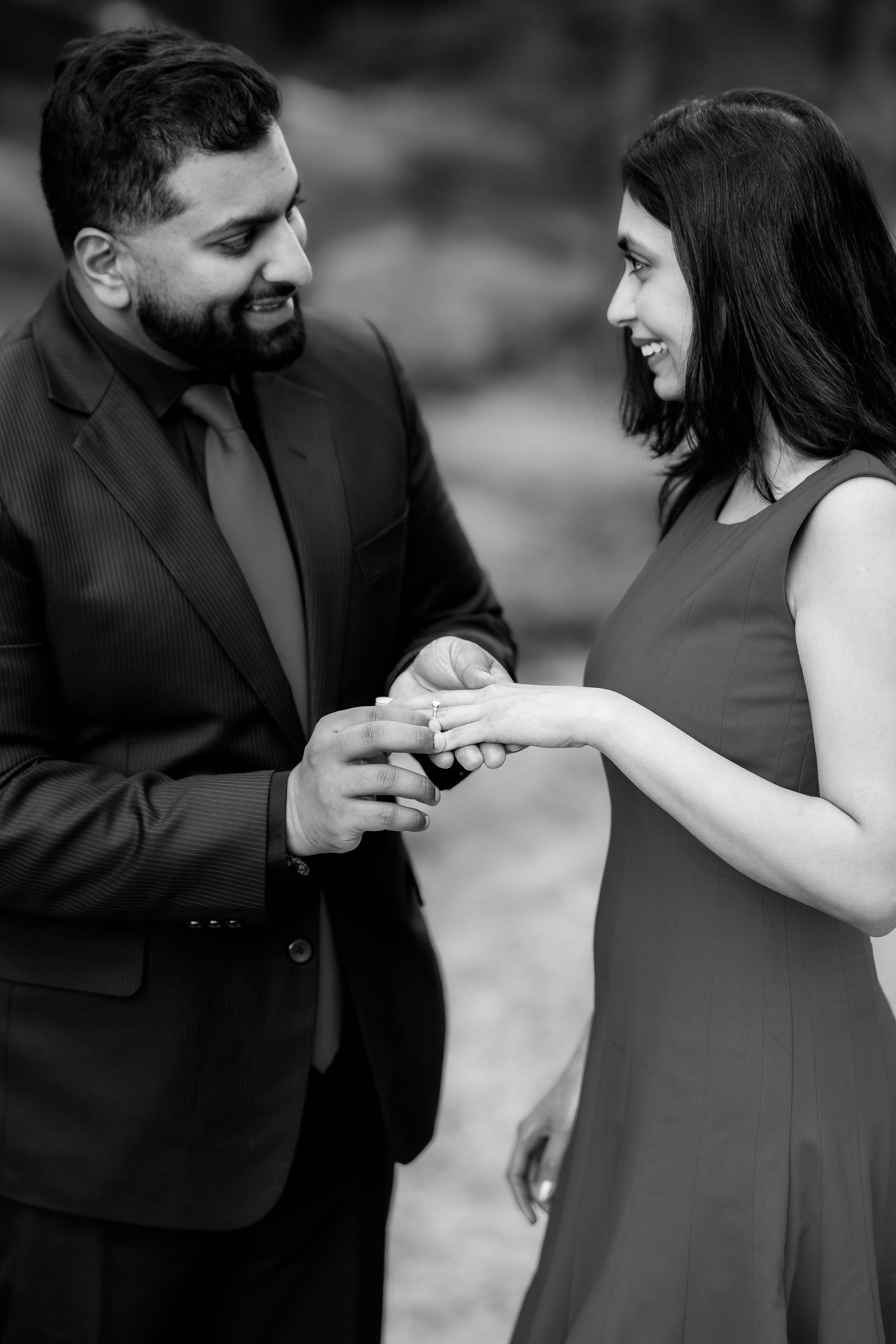 A couple exchanges rings during an intimate outdoor proposal moment.