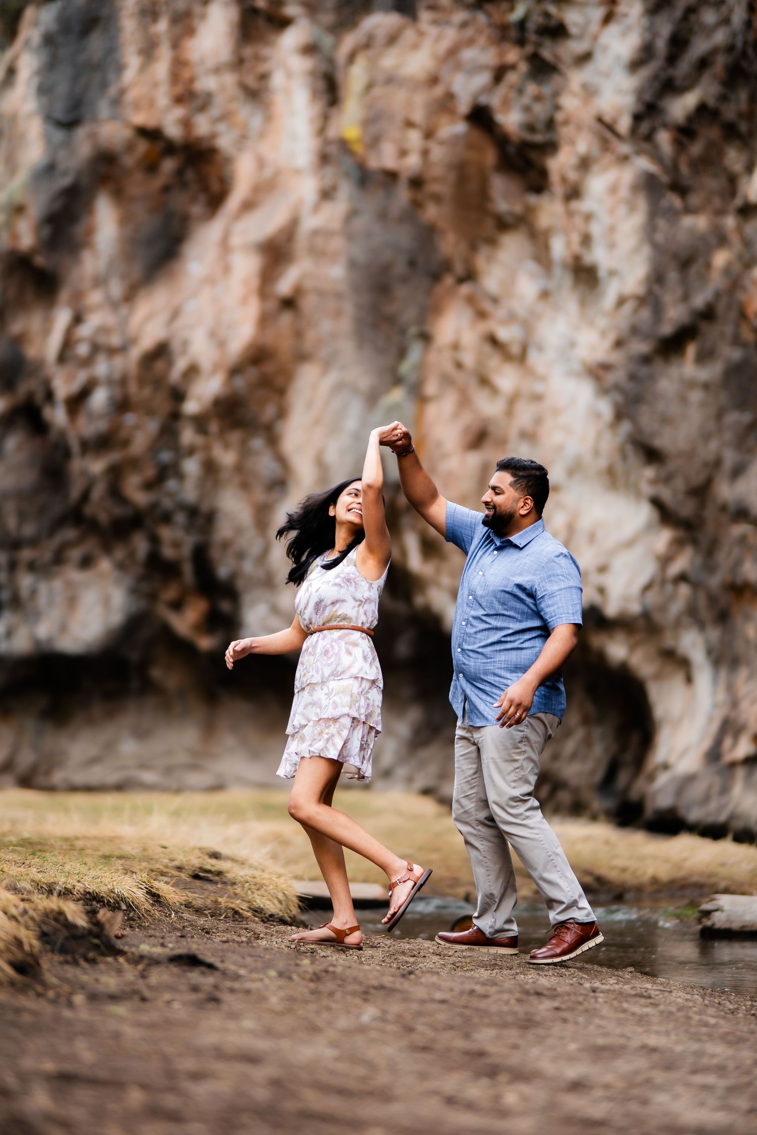 A couple dances joyfully together against a backdrop of dramatic rock formations.