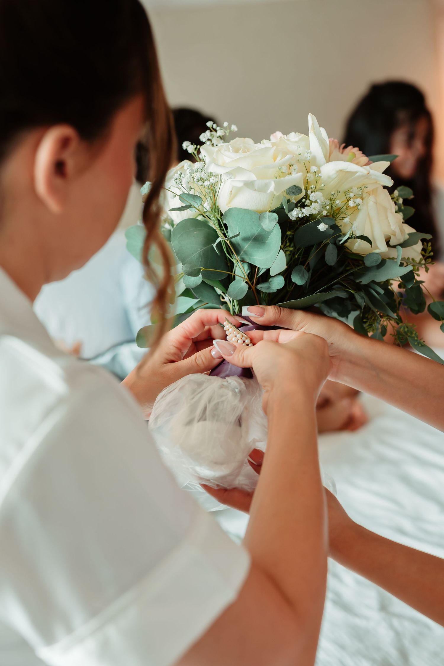 Row of bridesmaids in white dresses holding white and green floral bouquets.