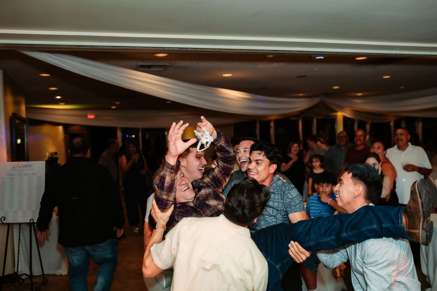 People dancing and celebrating at a lively party in an indoor venue with dim lighting.