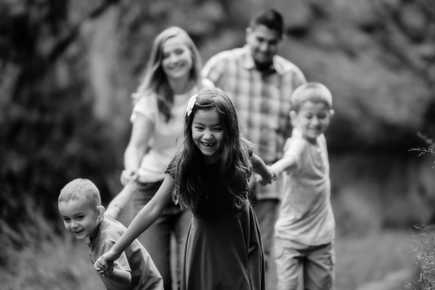A joyful outdoor family photoshoot session with people laughing and playing in a natural setting.