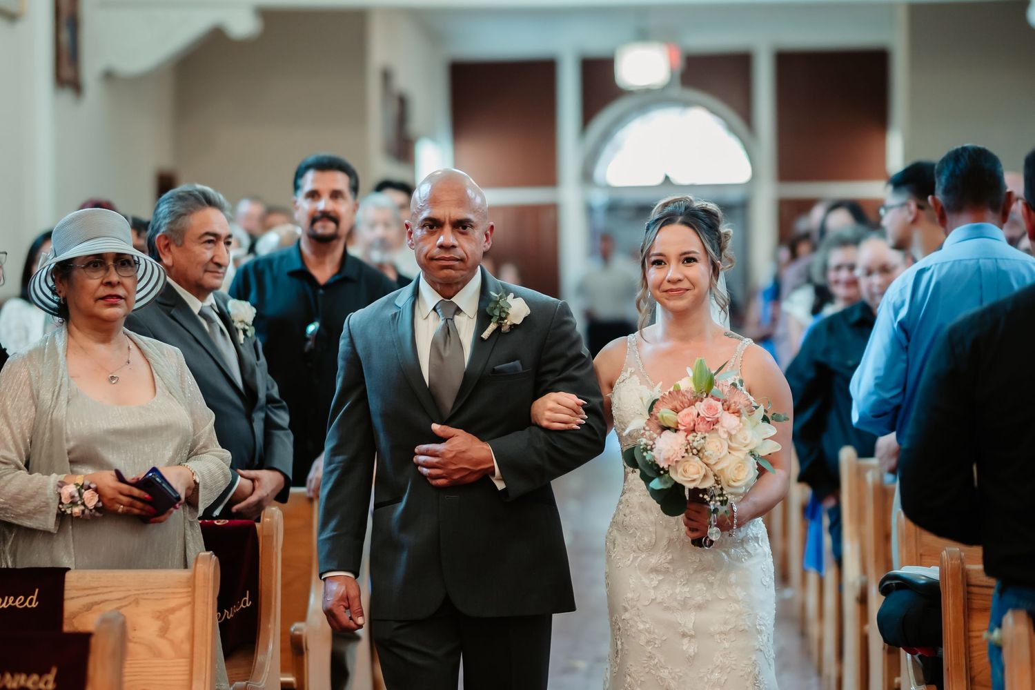 Wedding ceremony taking place in a church with wooden pews and guests in formal attire.