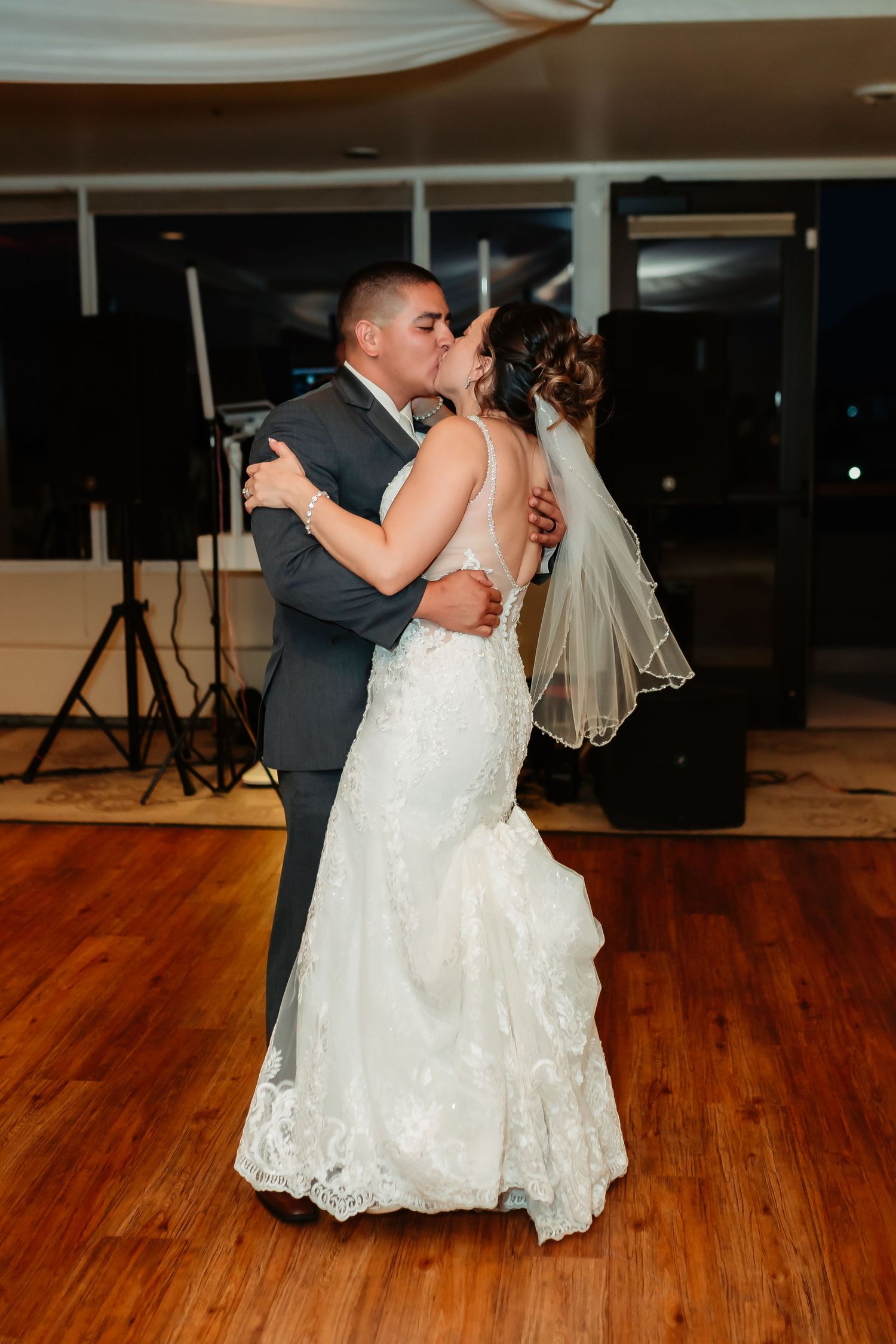 A couple performs their first dance at their wedding reception on a wooden dance floor.