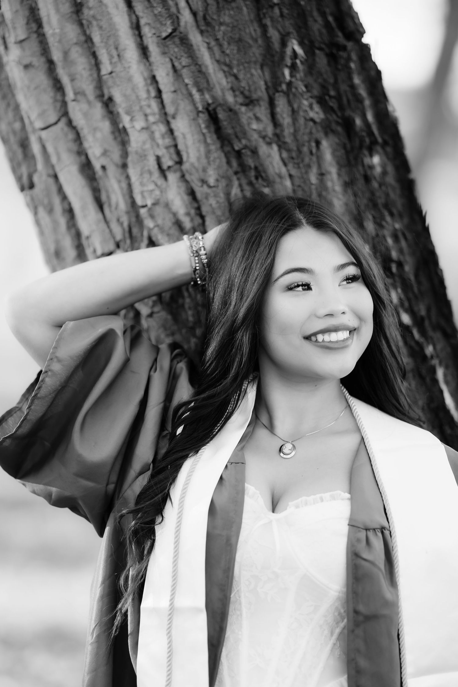 A collection of black and white portrait shots taken against a backdrop of tree trunks.