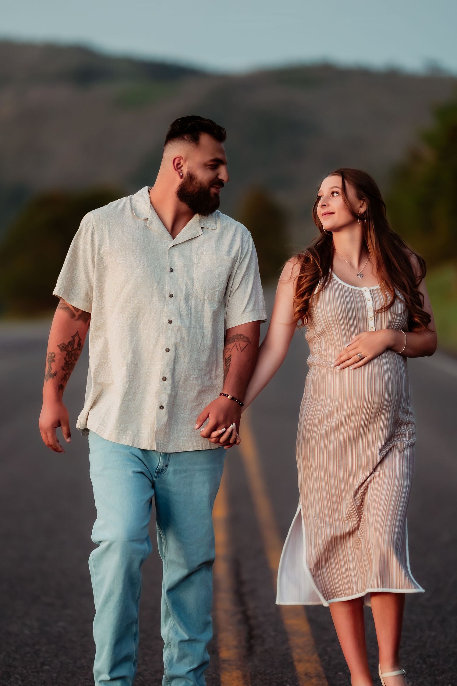 A couple in light summer outfits share romantic moments while walking together during golden hour.