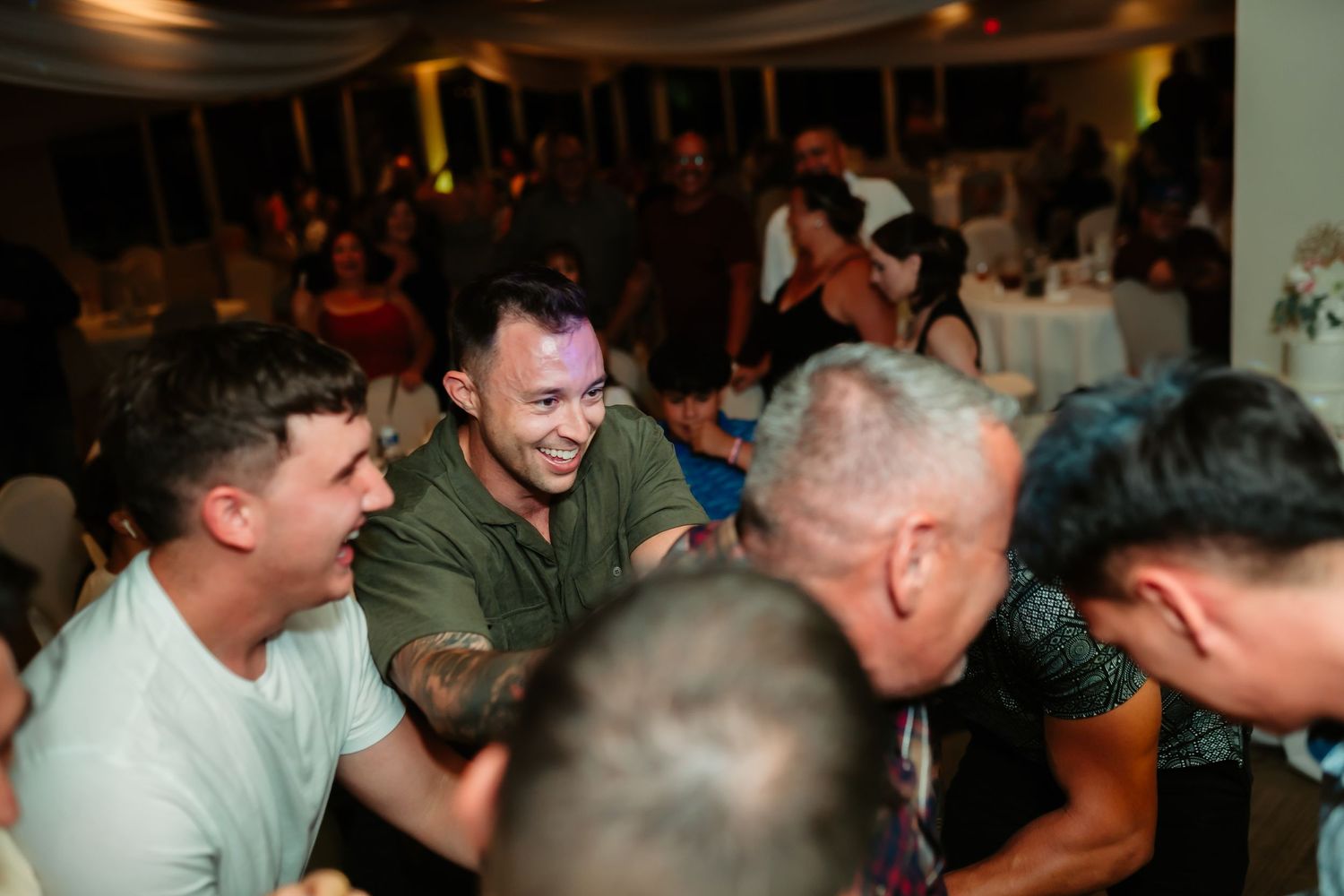 Wedding guests share laughter and dance moves during an energetic reception celebration.