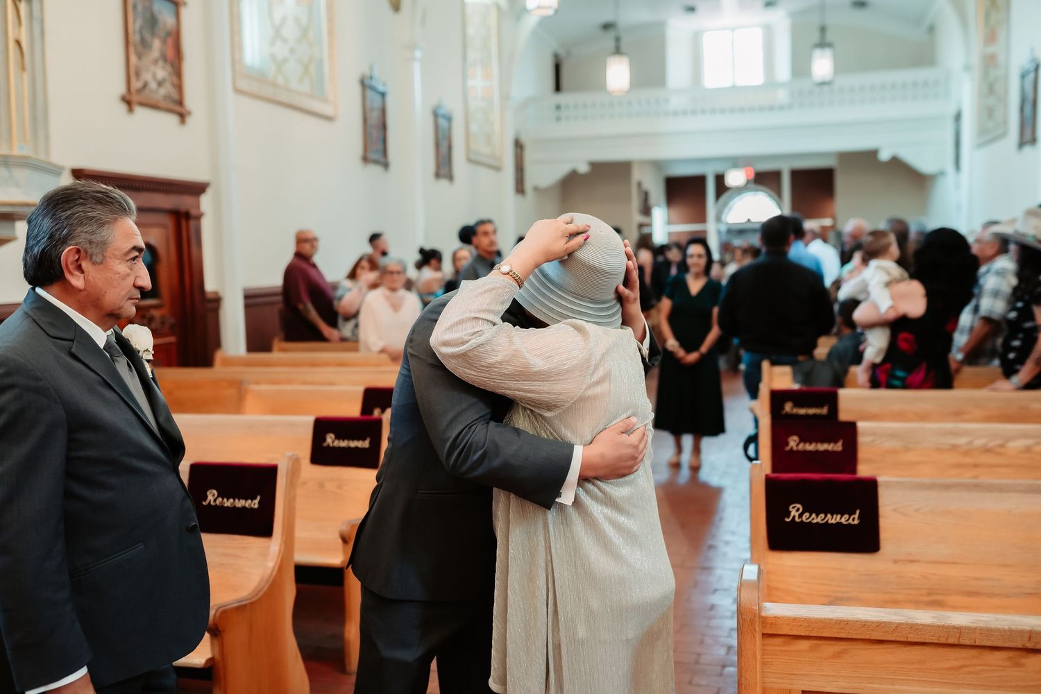 Wedding ceremony taking place inside an elegant church with ornate white interior and sunlit windows.