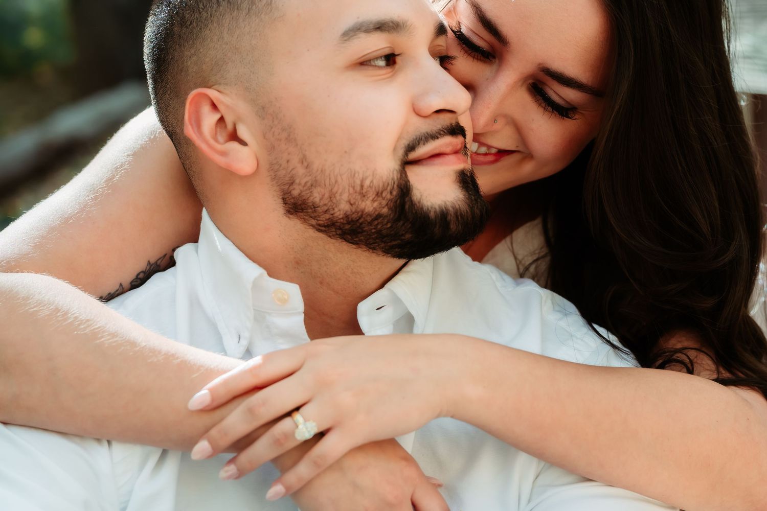 Two people share an intimate romantic moment while embracing in soft natural lighting.