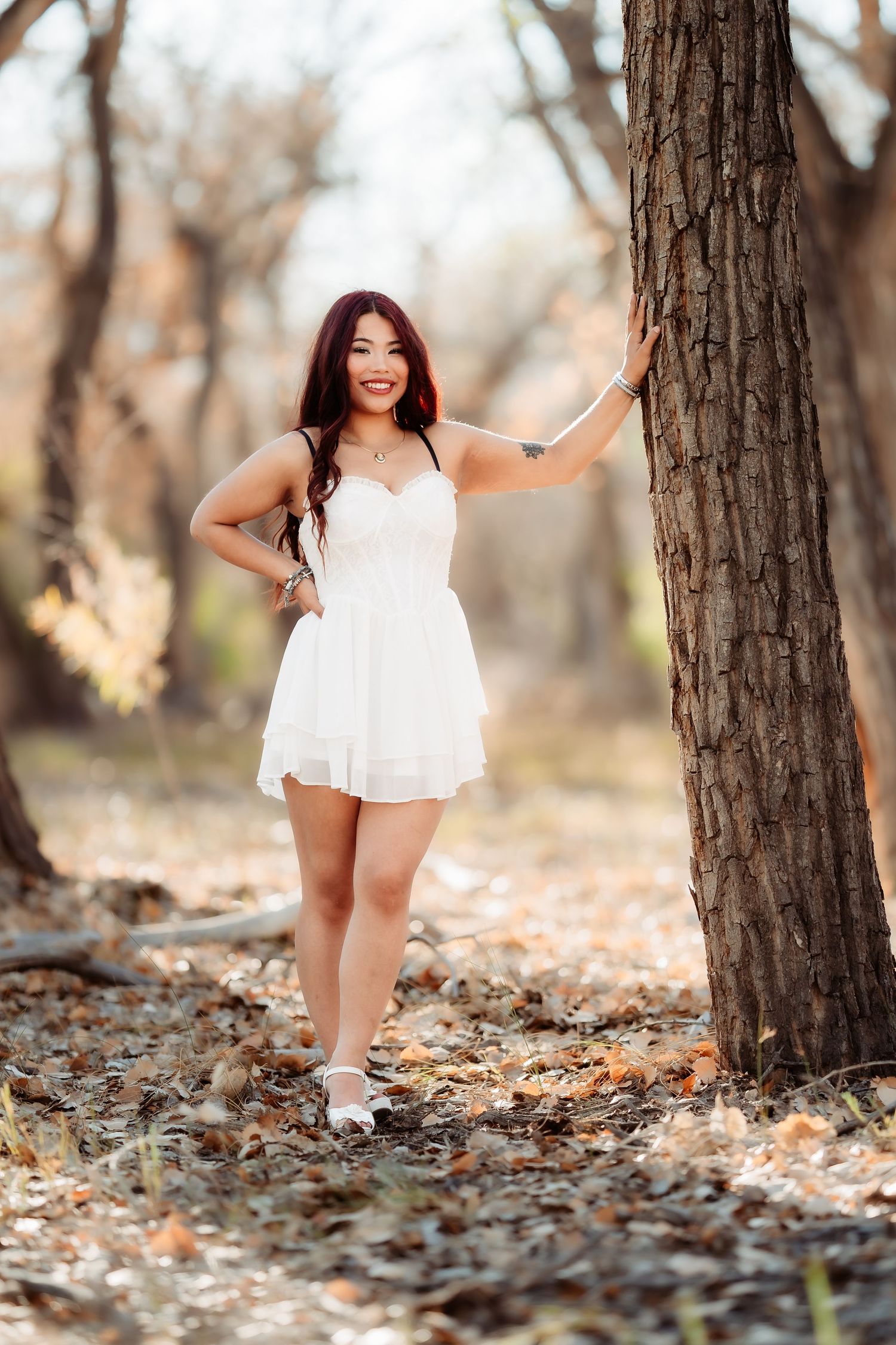 A series of outdoor portraits in a wooded setting with autumn leaves scattered on the ground.