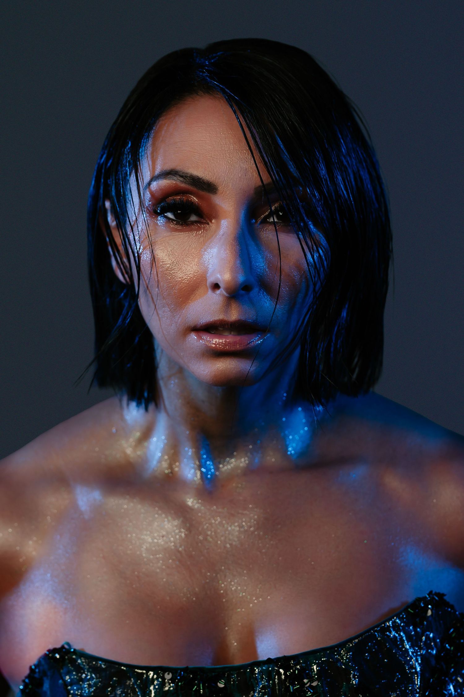 Artistic portrait series with dramatic blue lighting shows a figure with wet hair against dark background.