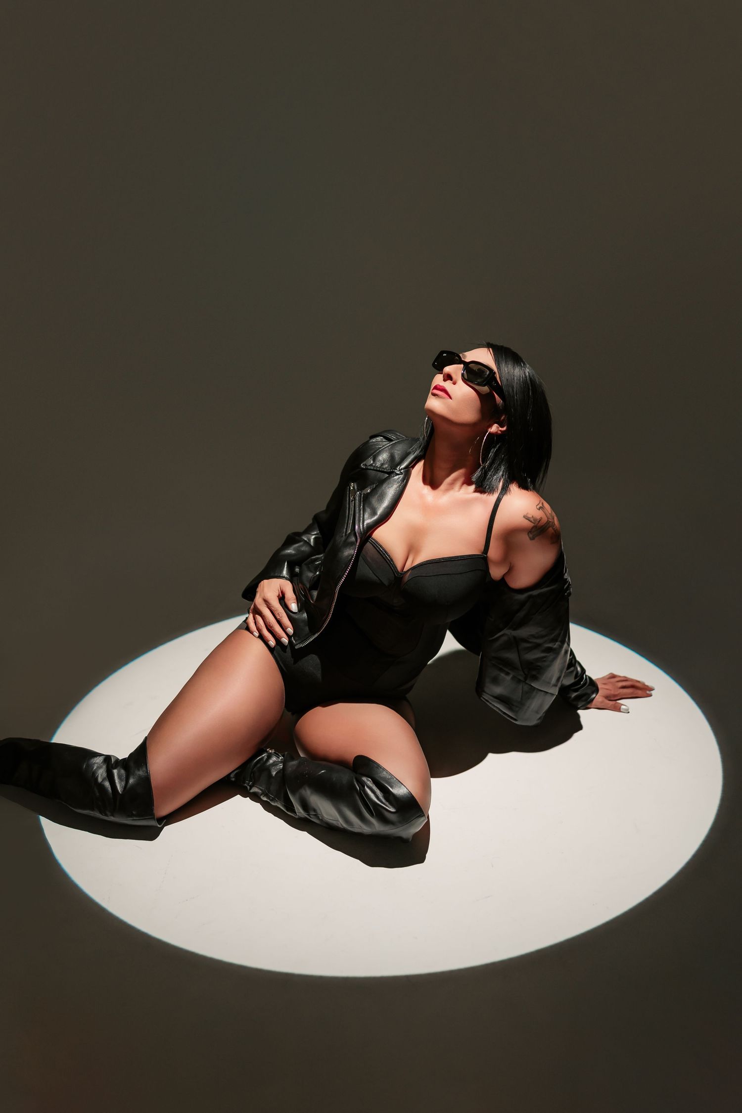 Artistic fashion photo series showing a figure in black leather reclining on a white curved surface against dark background.
