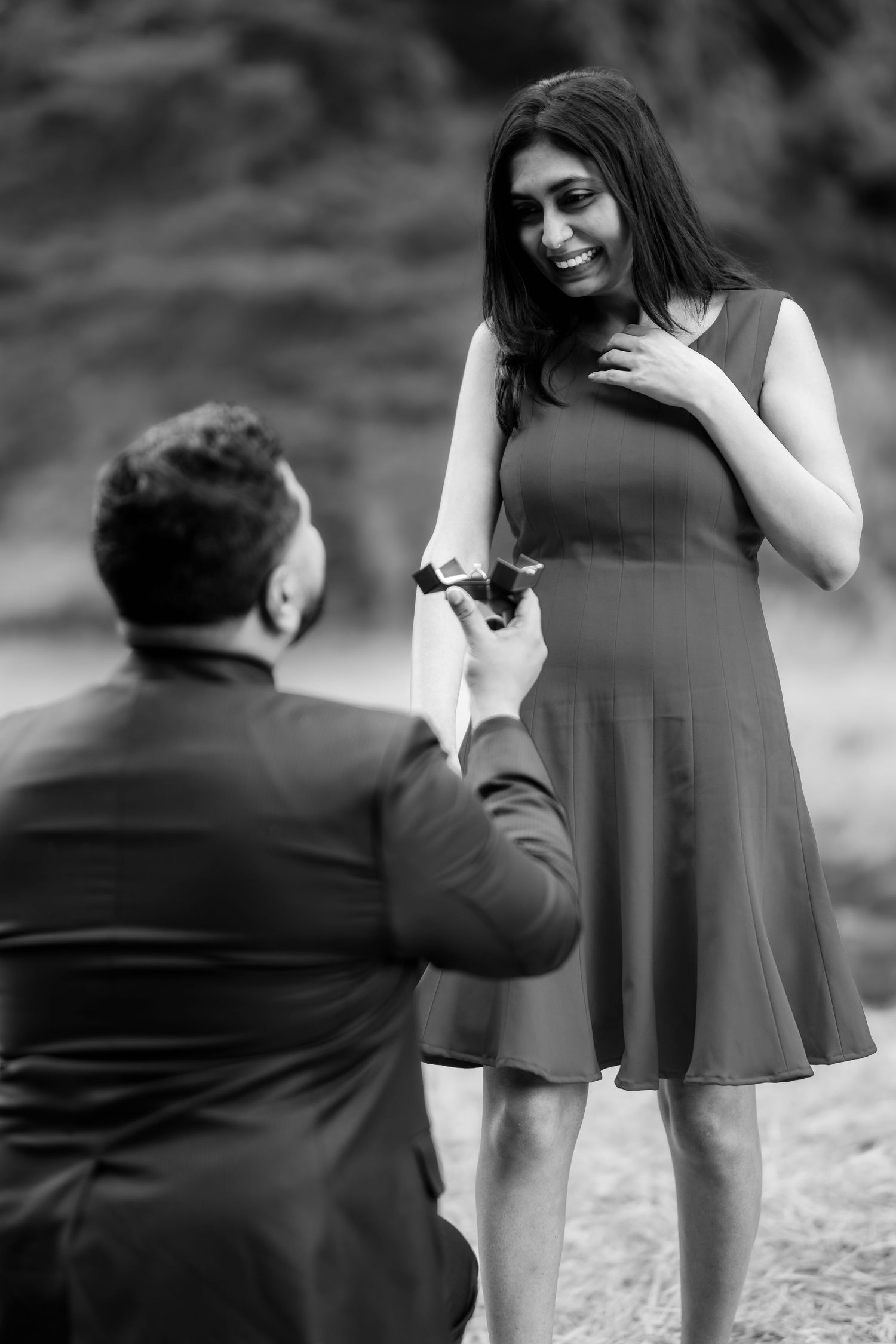 A heartfelt proposal moment captured in black and white photography outdoors.