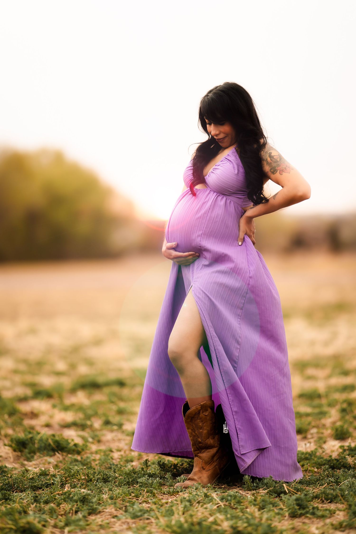 A person in a flowing purple dress twirls gracefully in a golden field during sunset.