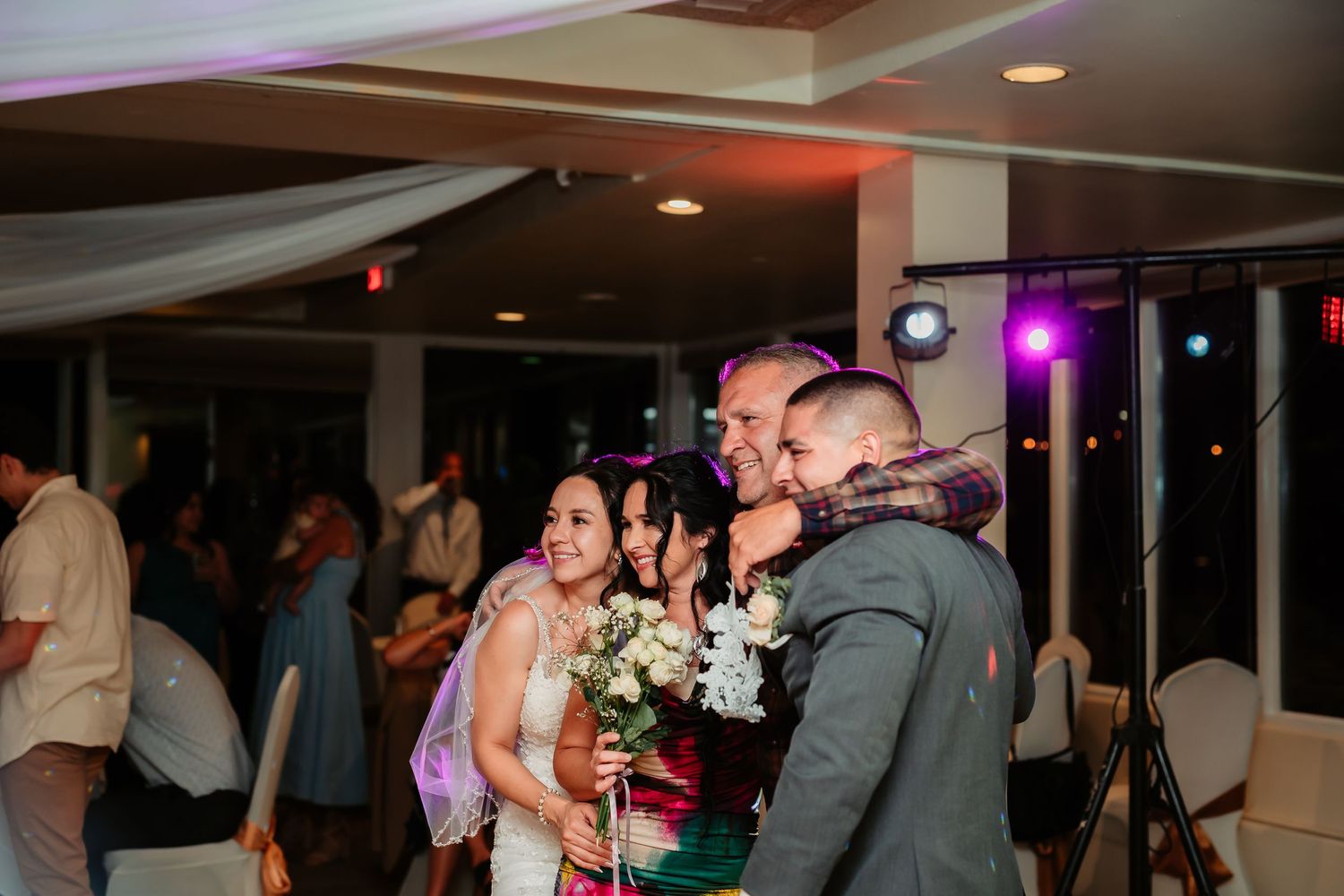 Wedding reception venue with decorative string lights and dancing silhouettes in a dimly lit room.