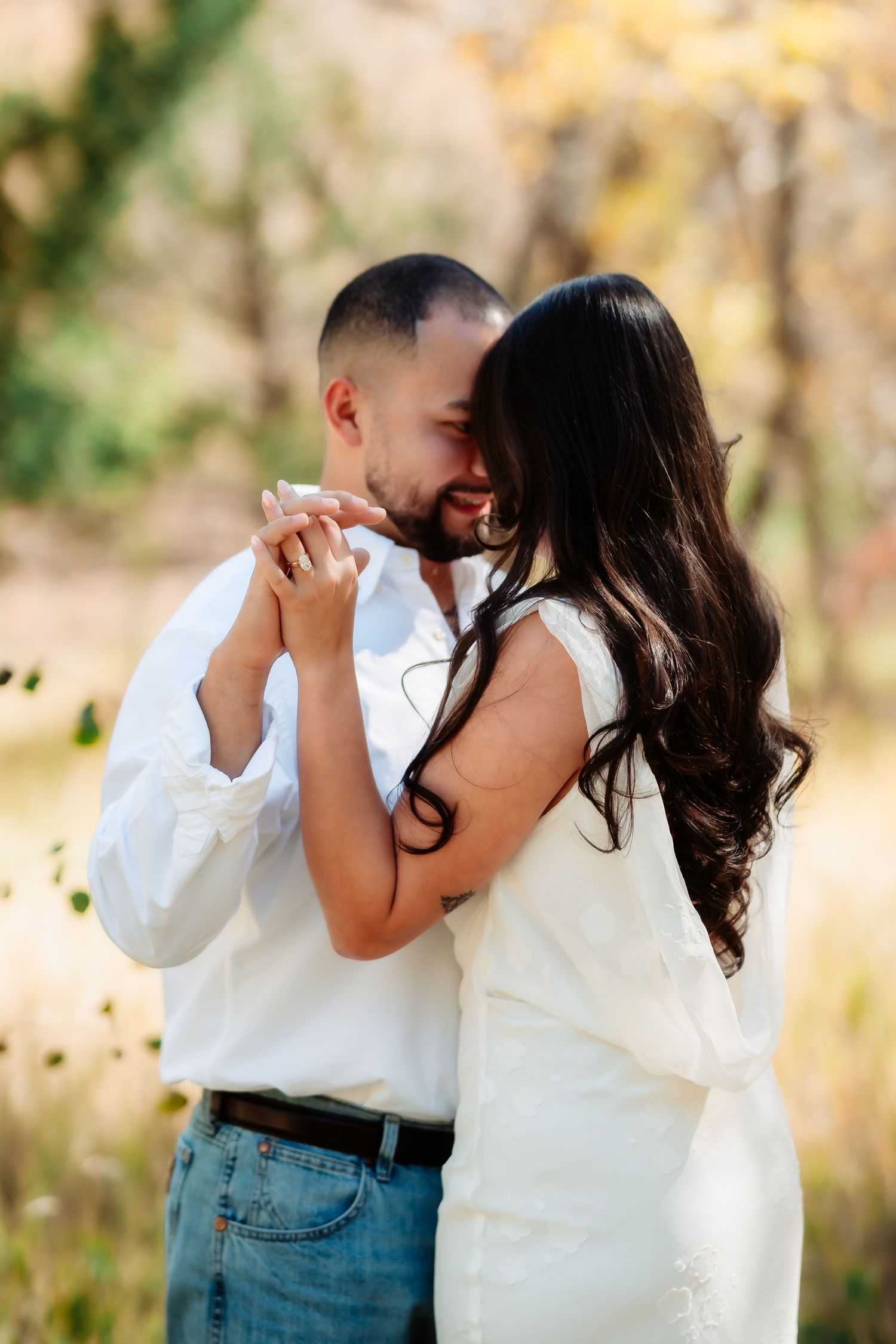 A couple in white tops and jeans share romantic moments in a series of outdoor photos at sunset.