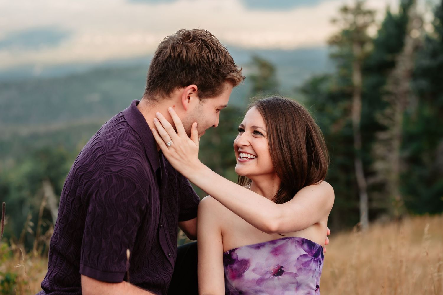 Couple shares tender embrace during romantic mountain photo session at dusk.