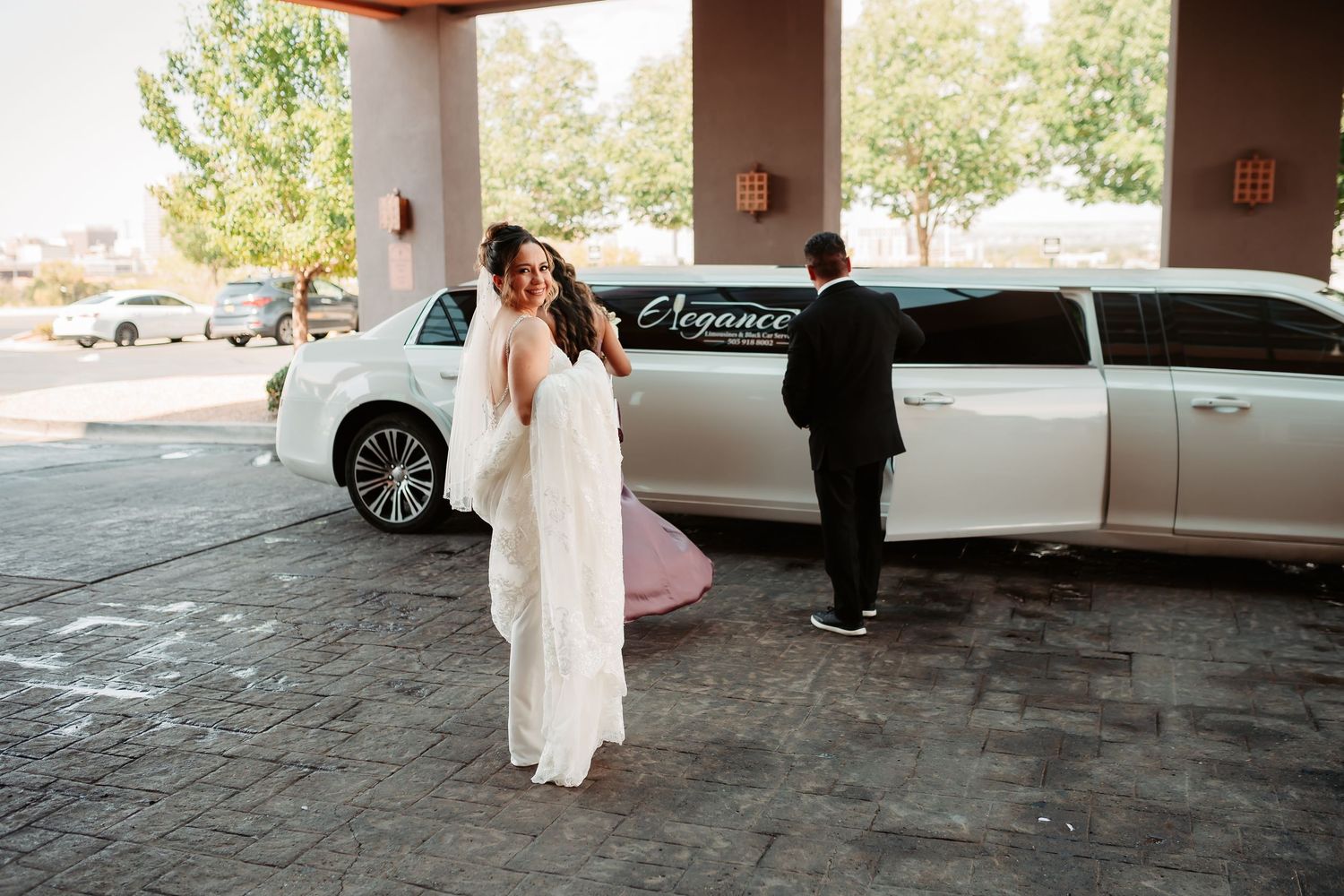 Wedding portraits taken under a covered walkway with white limousine in the background at a venue.