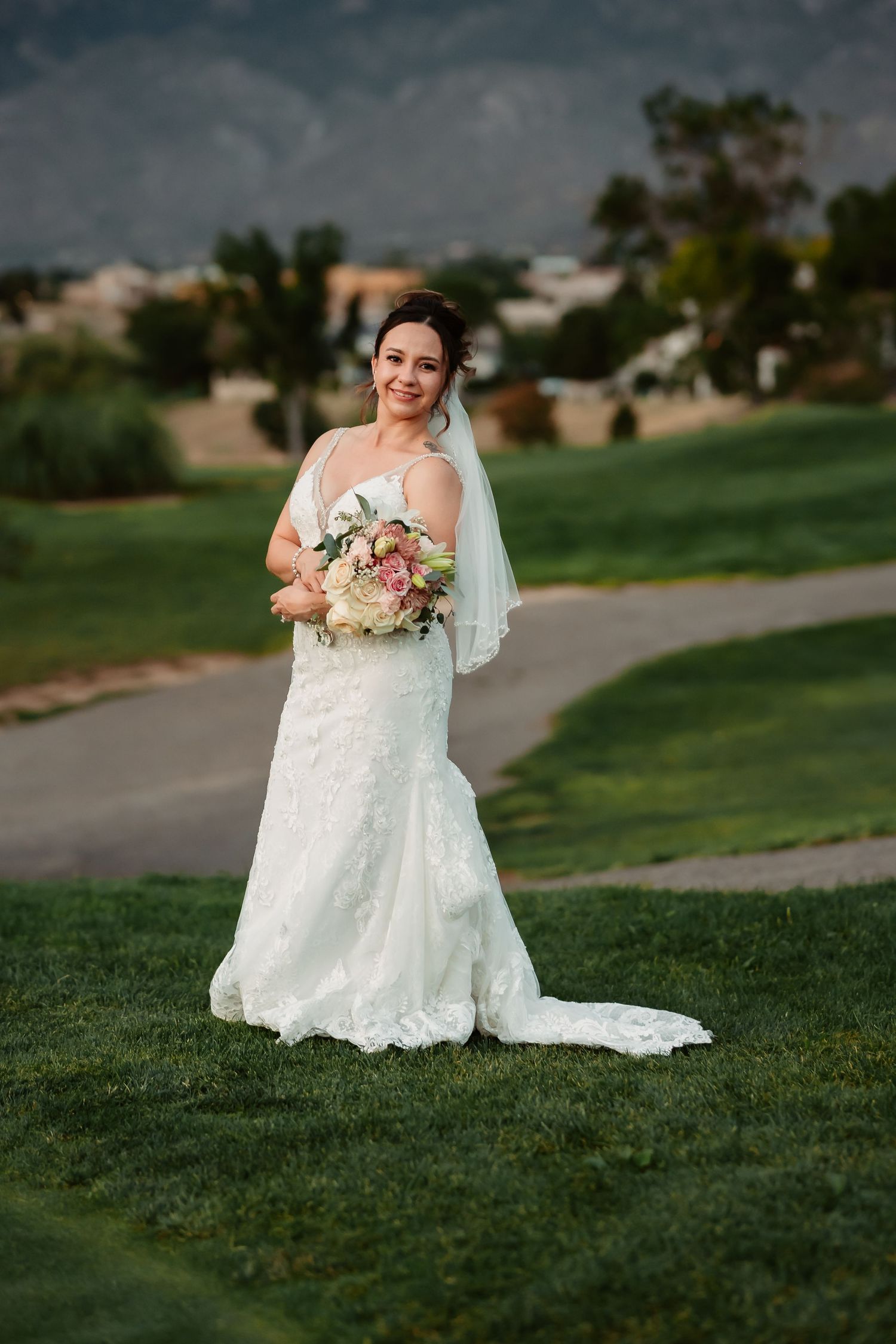 A wedding dress detail against a green lawn with mountains in the background.