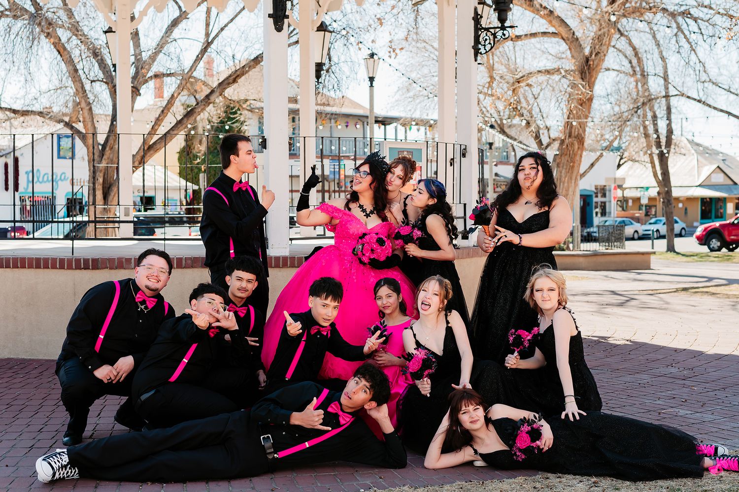 Group photo shoot outdoors with dancers wearing pink and black outfits against winter trees.
