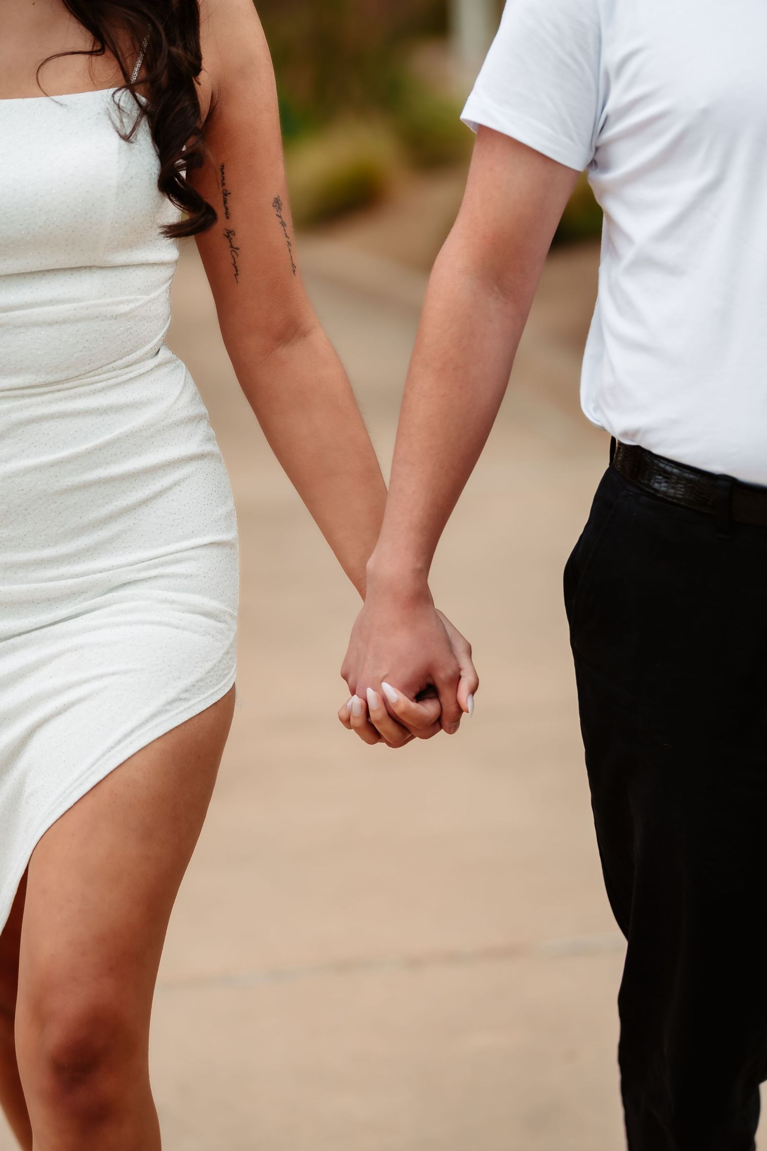 A couple holds hands while standing close together outdoors.
