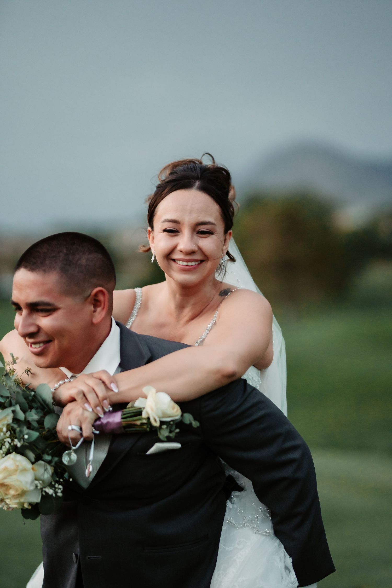 Candid moment of newlyweds laughing and embracing during outdoor photo session.