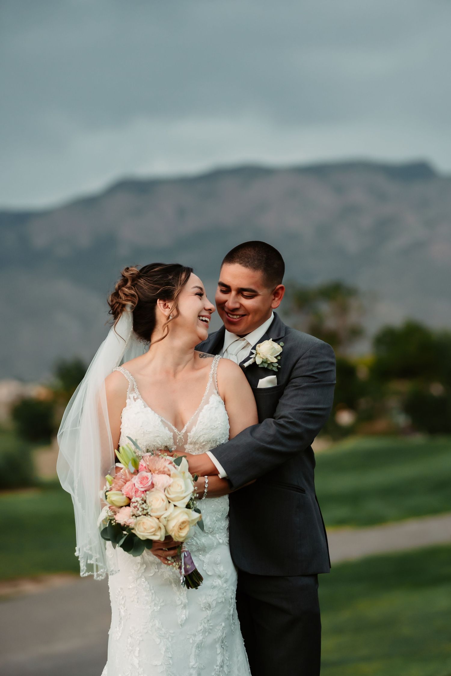 Wedding portrait at sunset with mountain backdrop and couple holding bouquet.