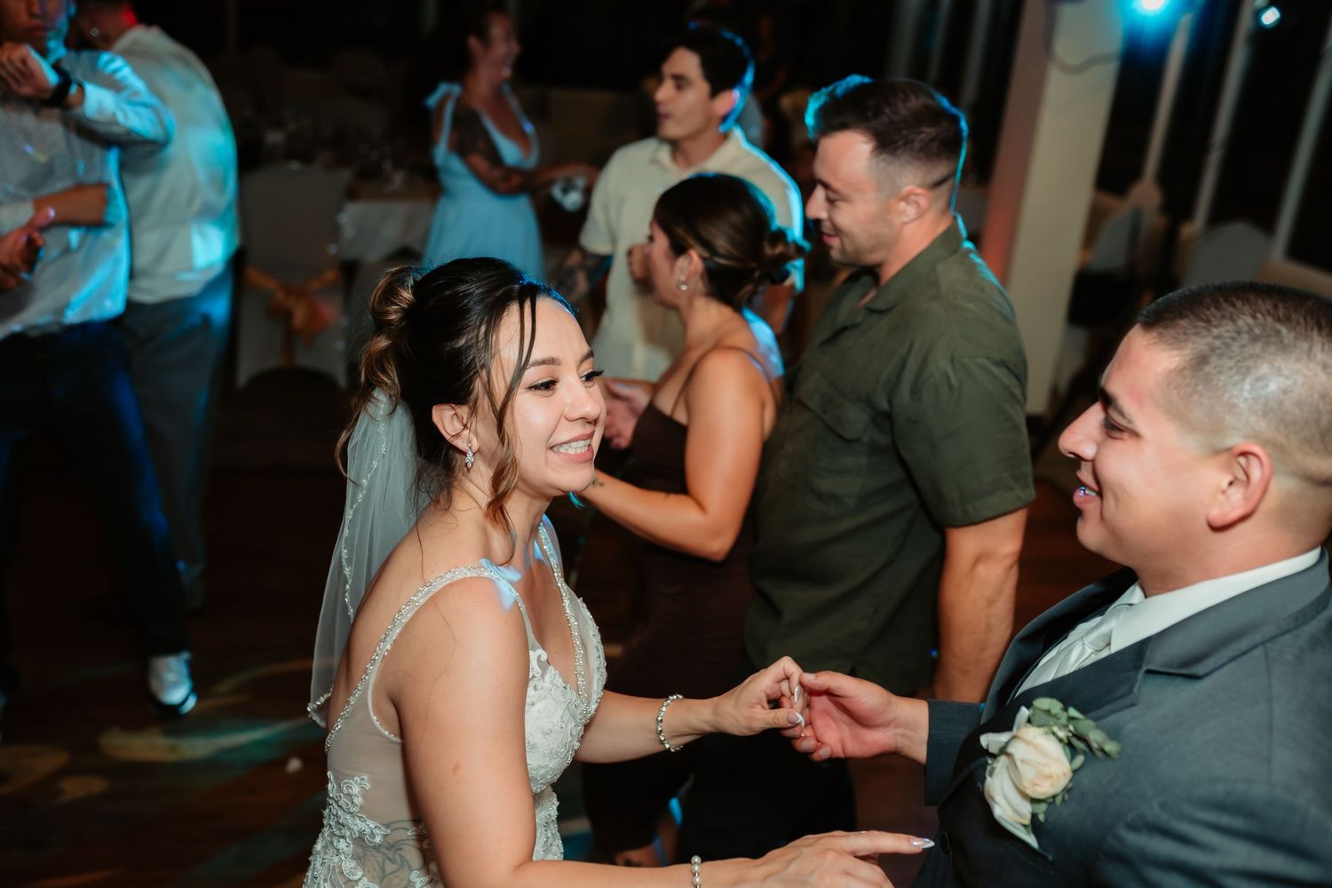 A couple shares their first dance together at a wedding reception with colorful lighting in the background.