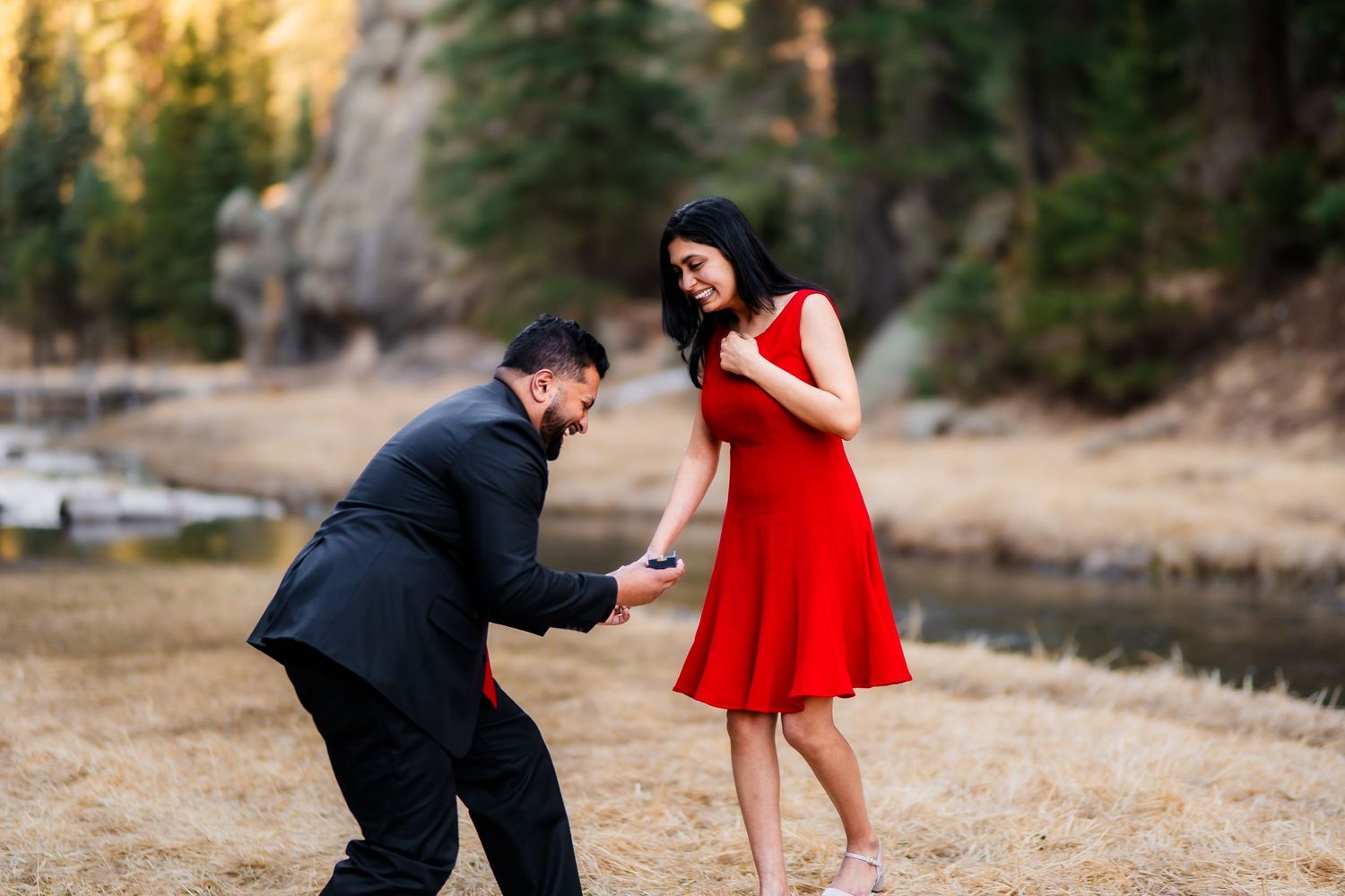 A joyful celebration moment between a couple wearing formal attire in a scenic mountain setting.