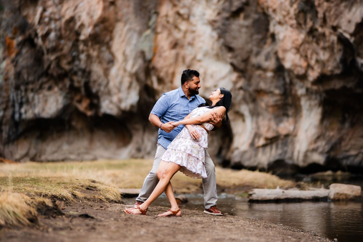 A joyful moment captured by a stream with dramatic rock formations in the background.