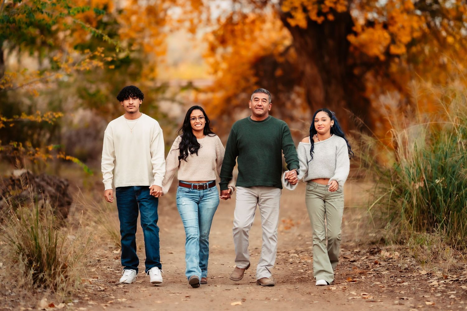 A group walking together on a path surrounded by warm autumn foliage and golden sunlight.