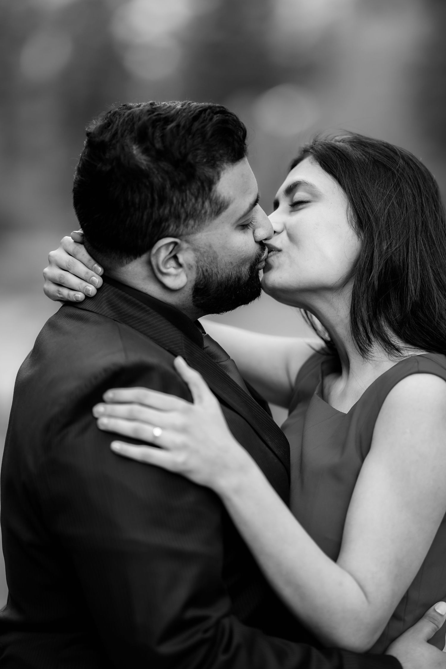 A romantic black and white portrait of a couple sharing a passionate kiss.