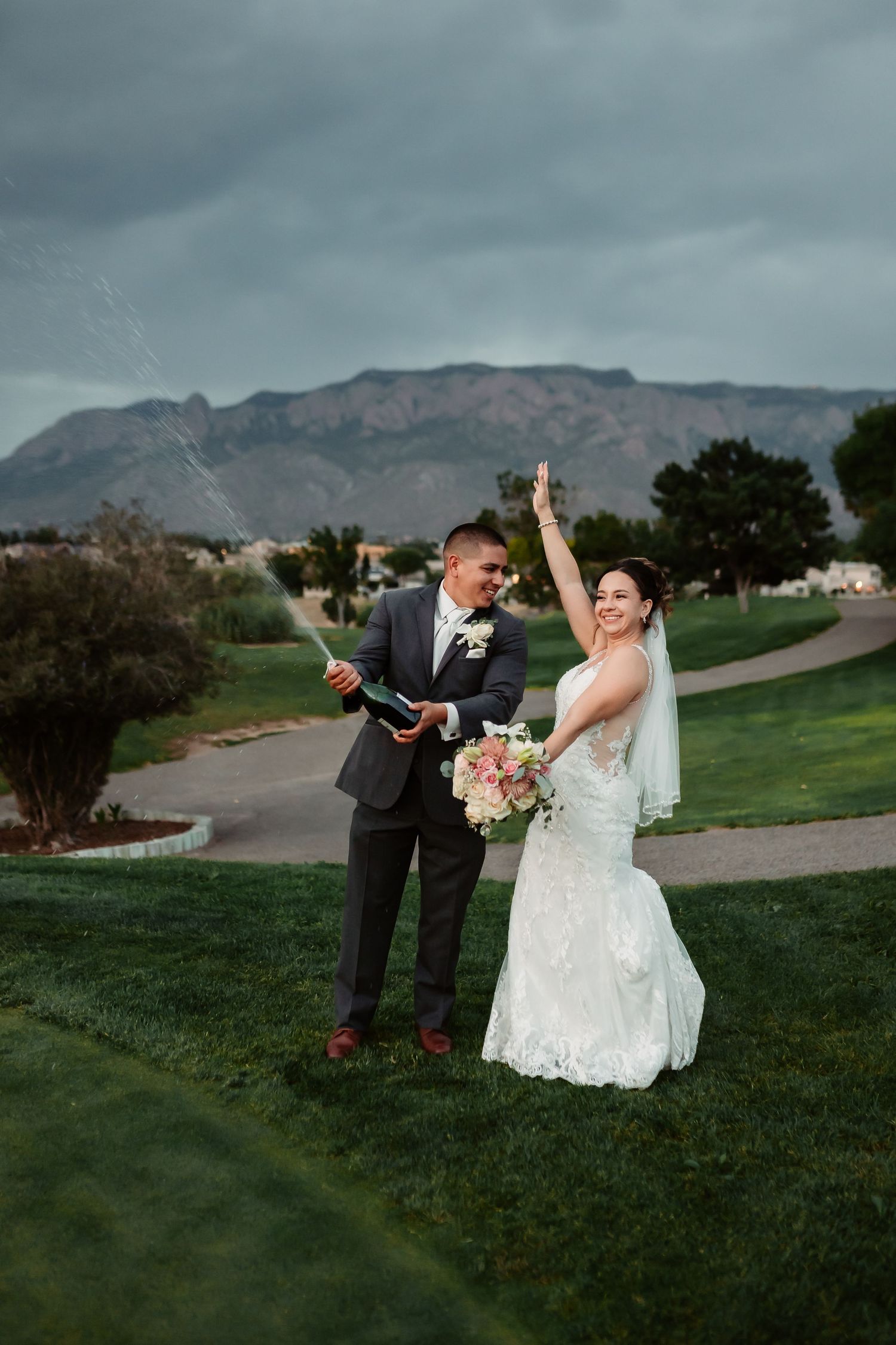 Wedding couple shares a celebratory moment on a golf course with mountain views.