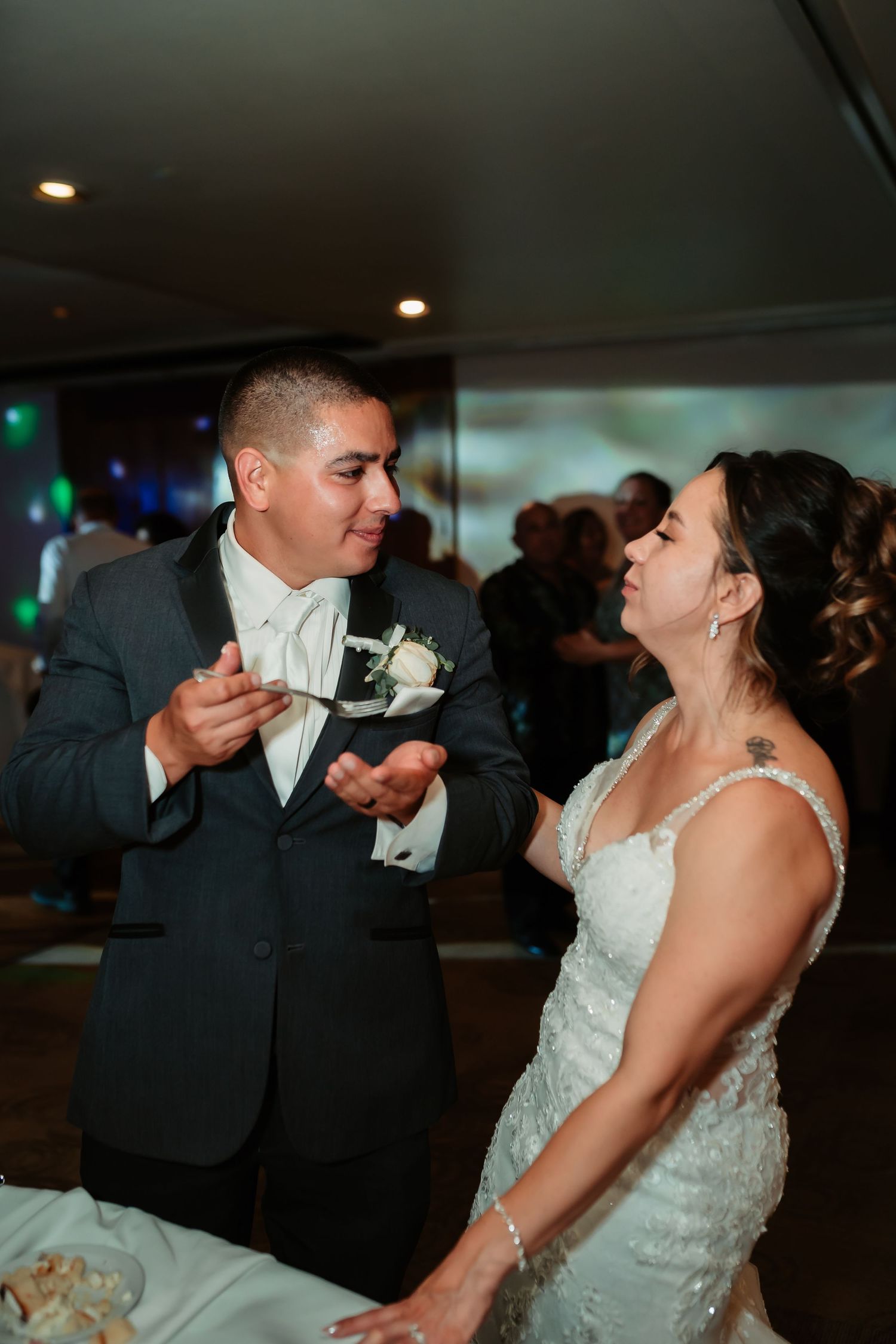 Newlyweds share a playful moment while feeding each other wedding cake.