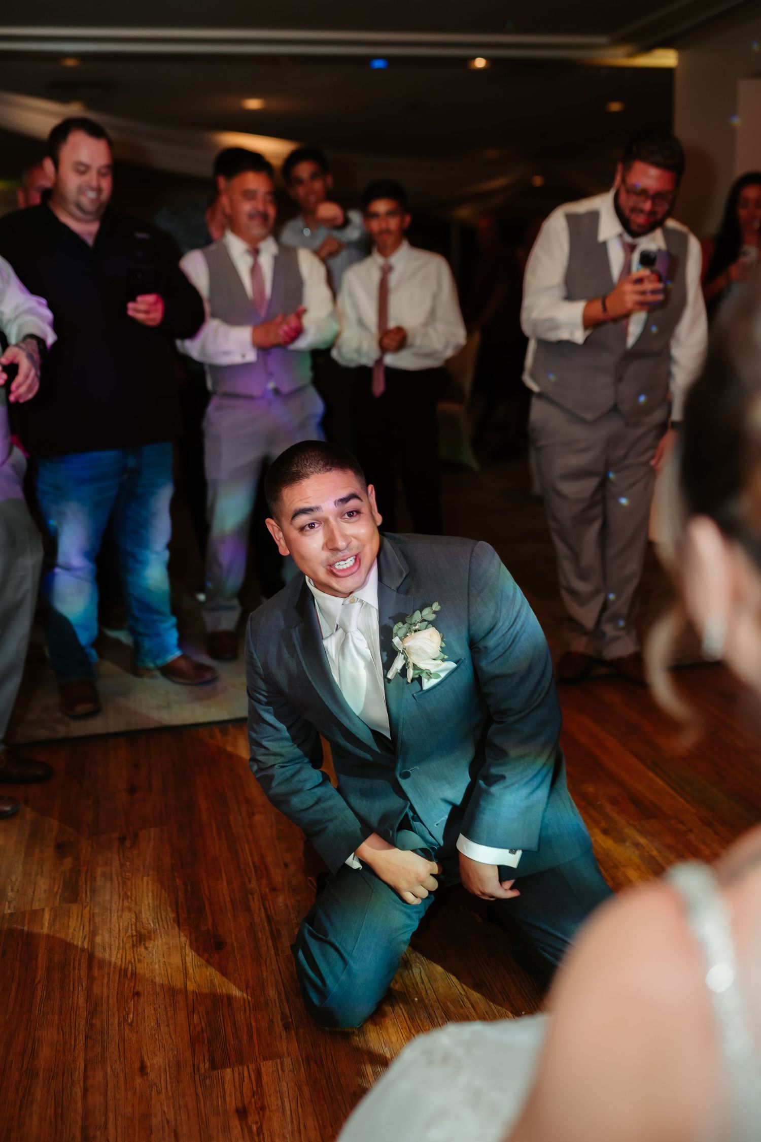 Wedding party members perform an energetic dance routine on a hardwood floor.