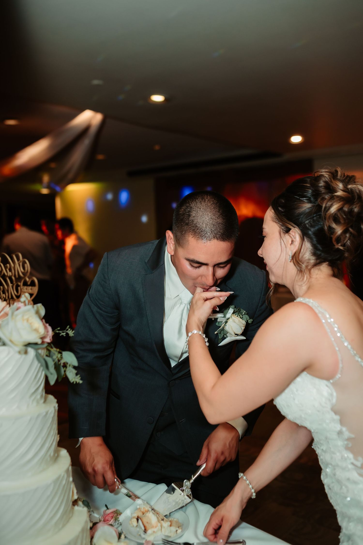 A couple enjoying an intimate dance moment at their wedding reception under moody lighting.