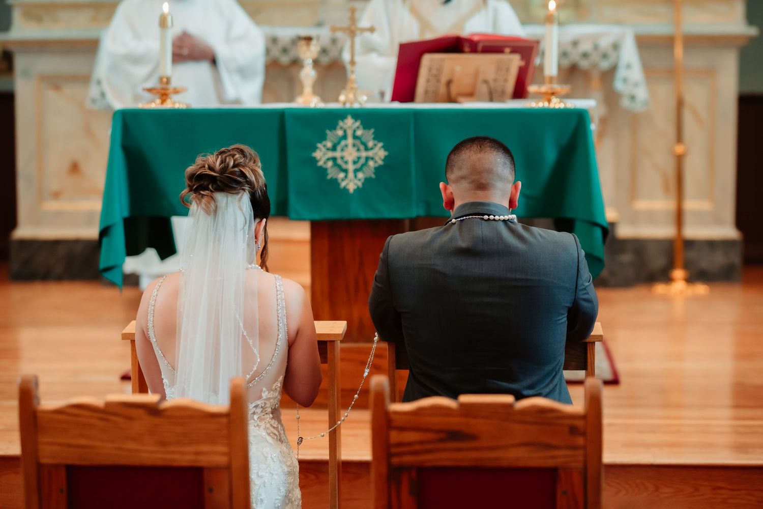 An intimate church wedding scene with a couple sharing a joyful moment while seated in wooden chairs.