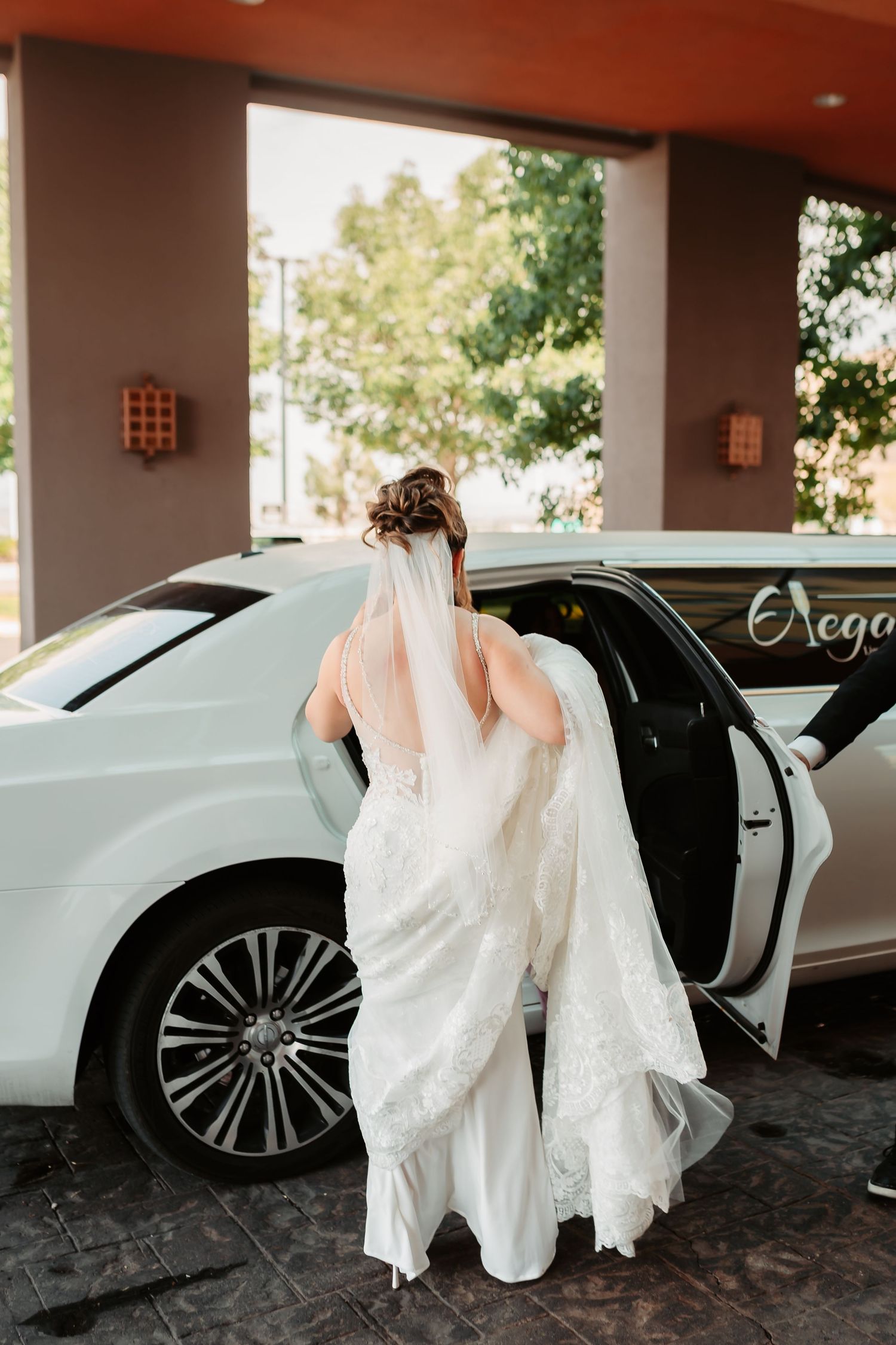 Sequence showing bride getting into white luxury wedding car while holding flowing dress train.