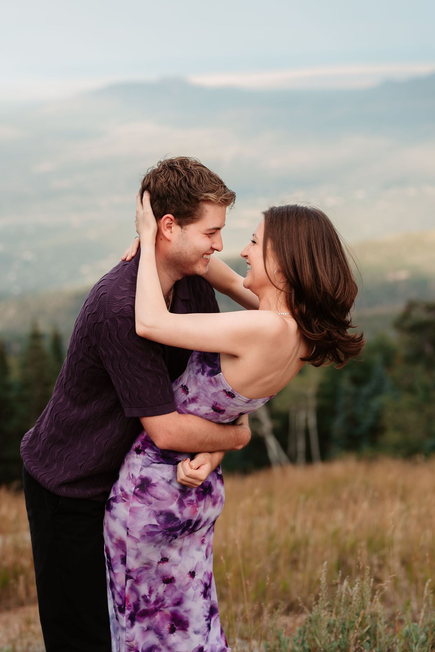 A romantic dip pose in a mountain meadow with sunset sky in background.