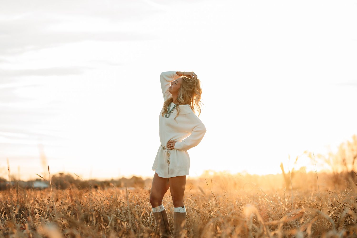 A couple stands together in a golden wheat field at sunset creating a romantic silhouette against the warm sky.