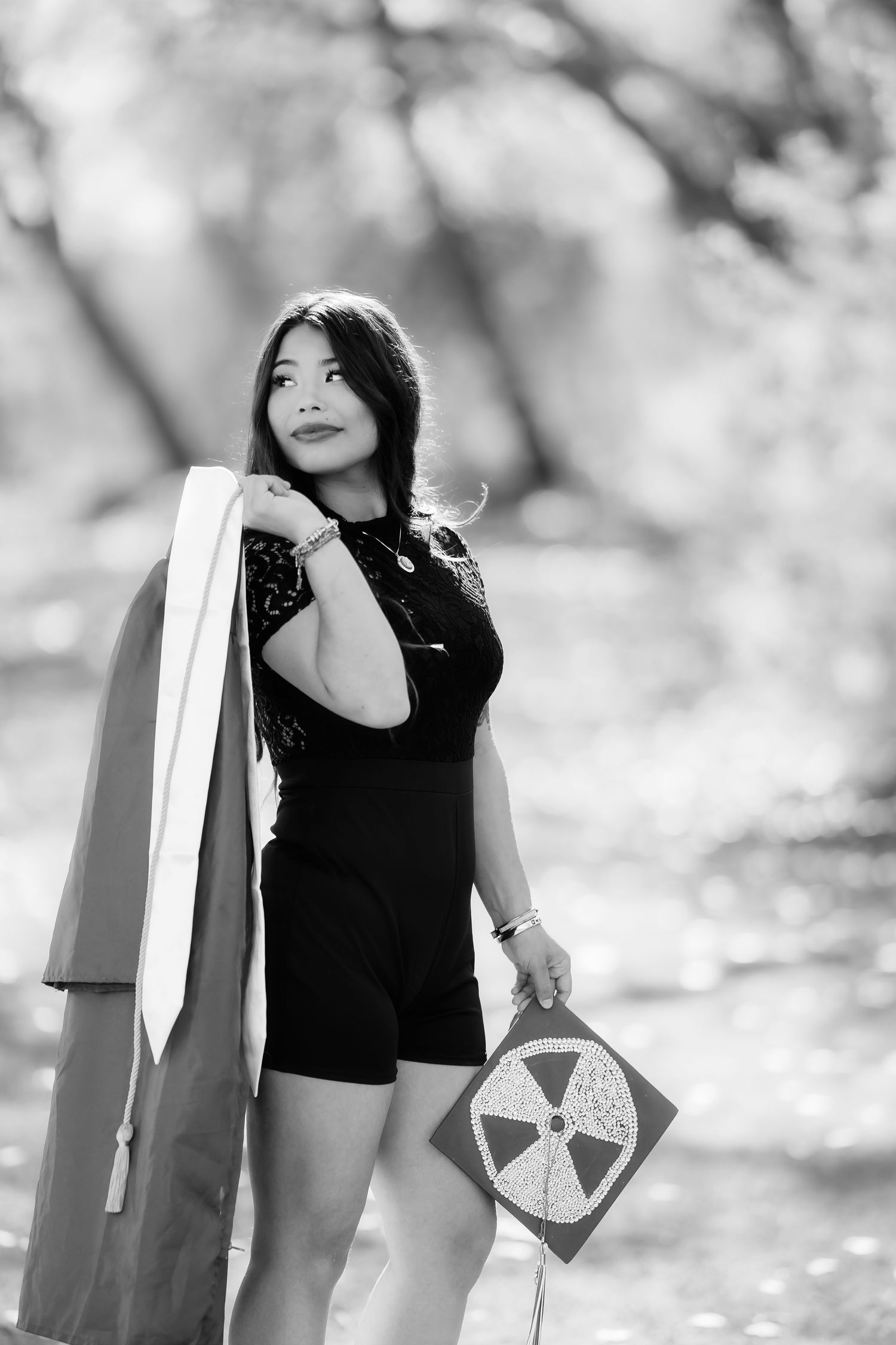 Black and white portrait with person holding coat and circular sign in natural setting.