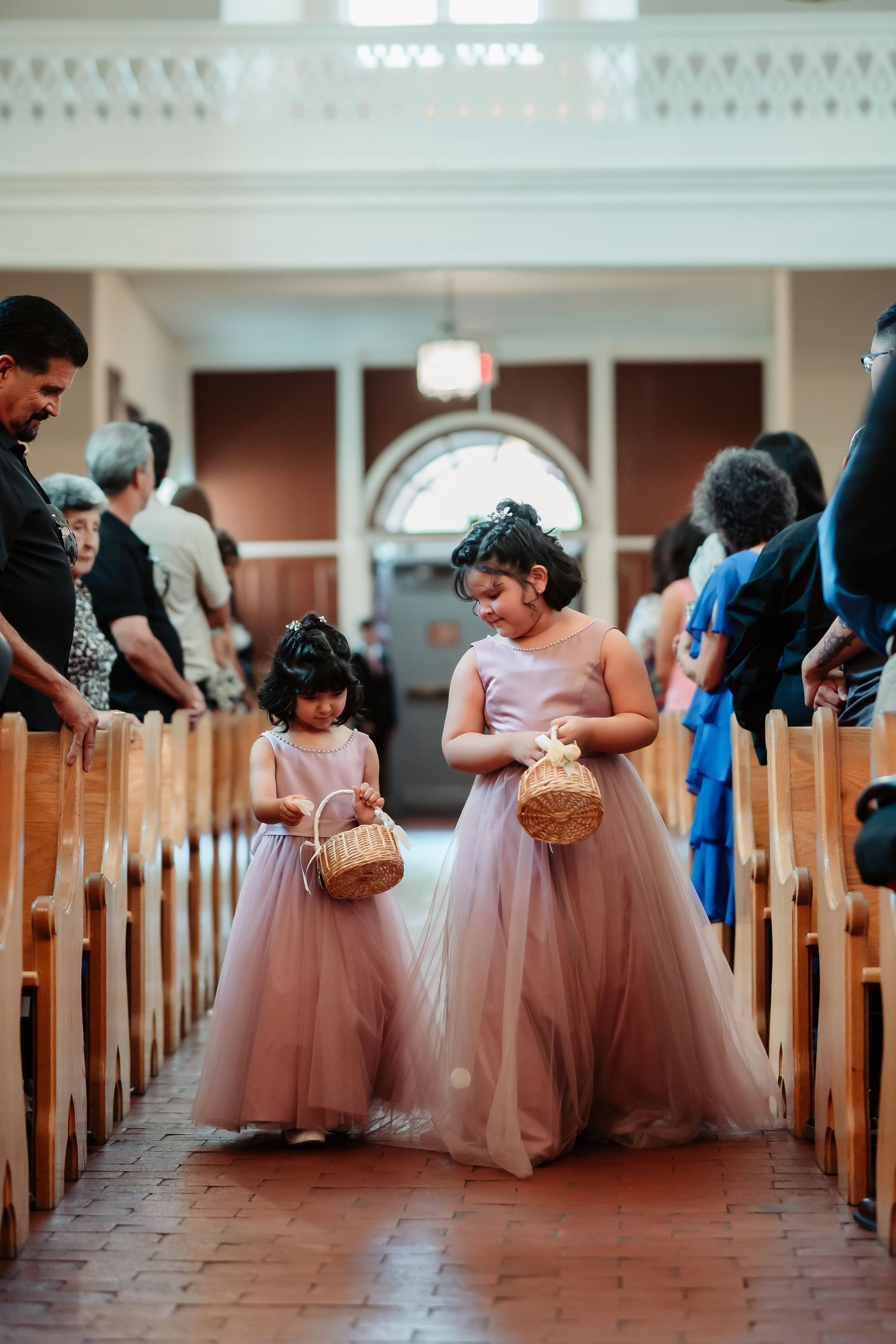 Bridesmaids in pink tulle skirts line the church pews during an elegant wedding ceremony.