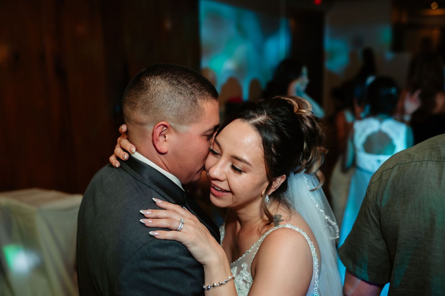 Newlyweds share an intimate dance moment under ambient lighting at their reception.