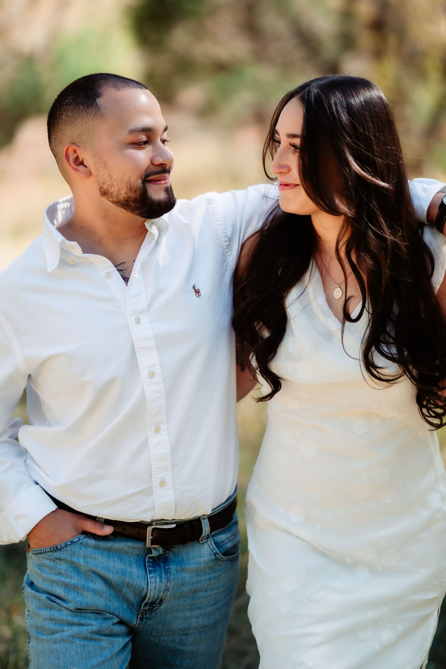 A romantic couple in white shirts and jeans share intimate moments together during an outdoor photo session.