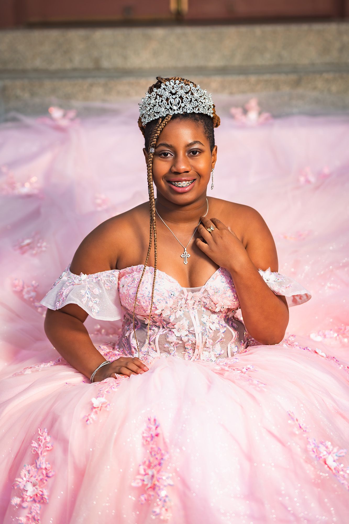 A stunning pink ballgown with off-shoulder details, floral appliques, and a sparkling crown creates a magical princess moment.