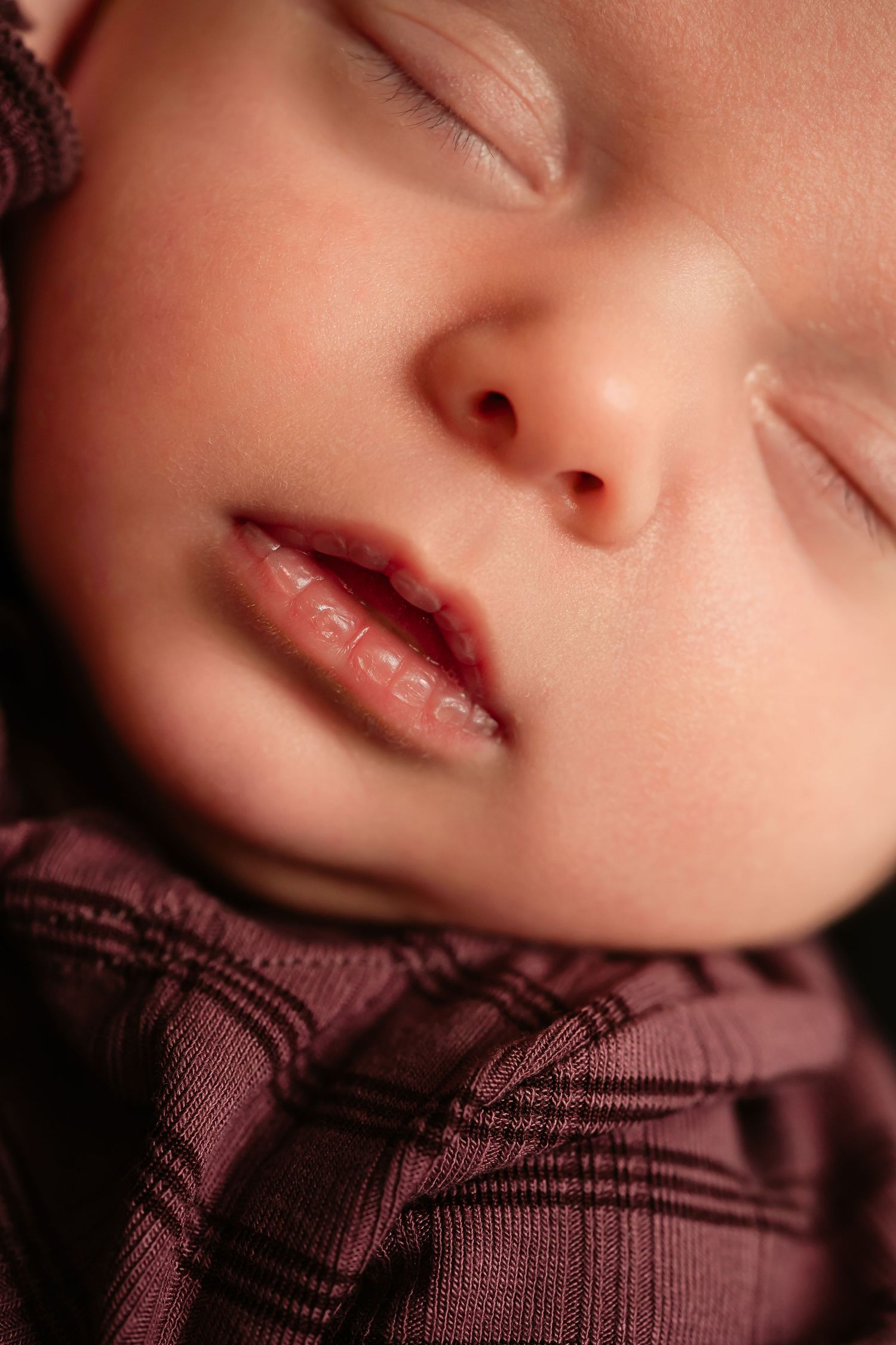 Close-up details of a sleeping infant wearing a brown knitted sweater.