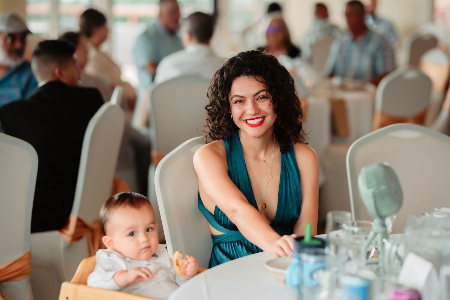 Family members celebrate special occasion during meal at restaurant reception with baby in high chair.