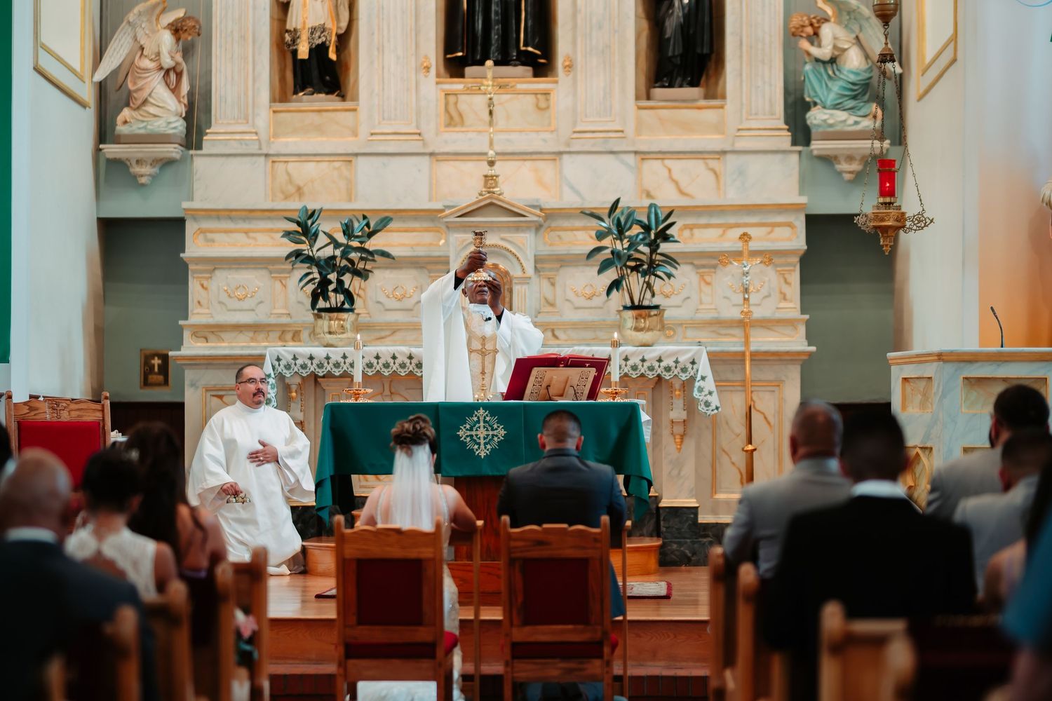 Church altar decorated with flowers and religious statues during wedding ceremony.