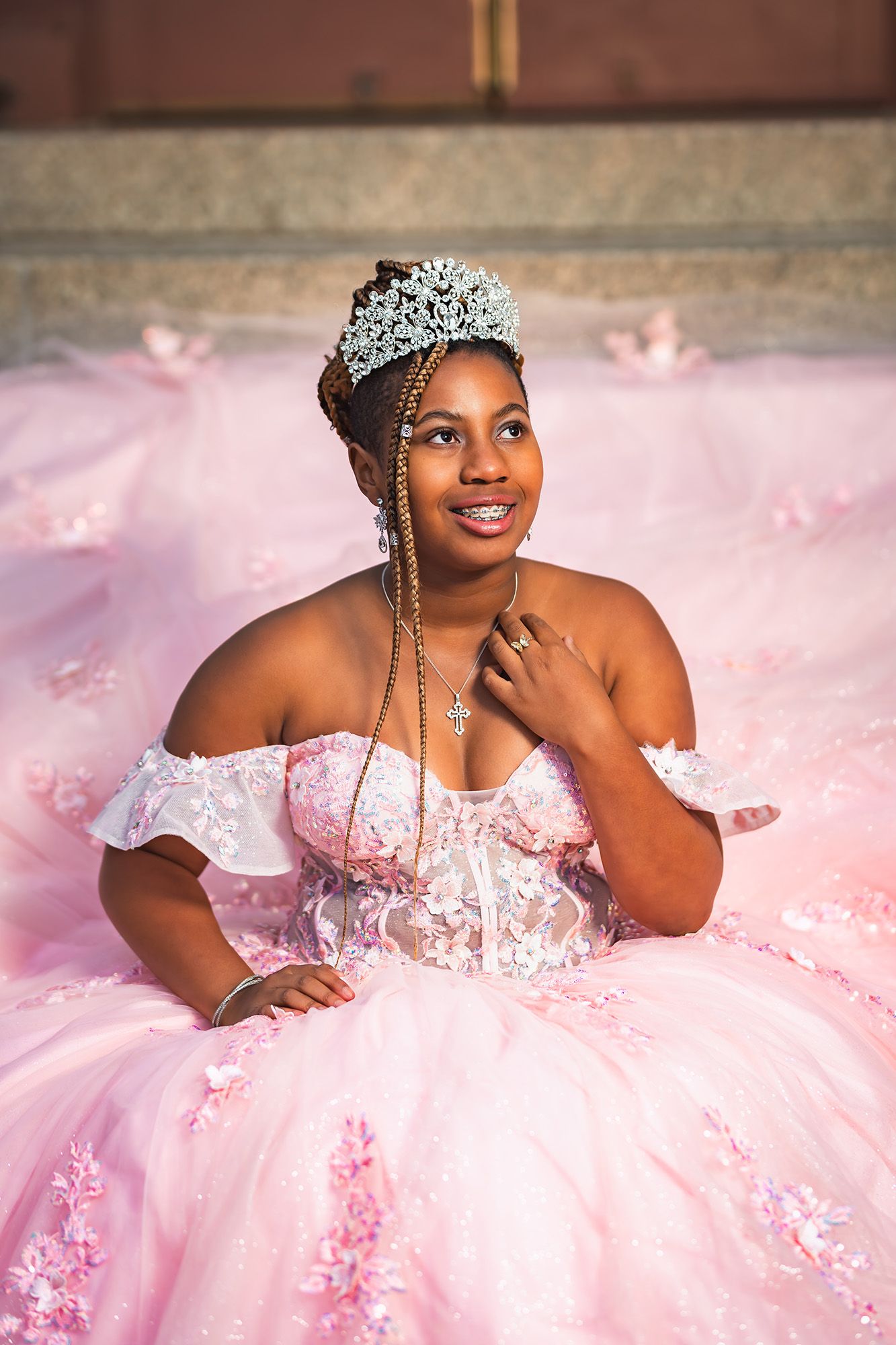 A person wearing a pink tulle ballgown with floral details poses gracefully in a series of elegant portraits.