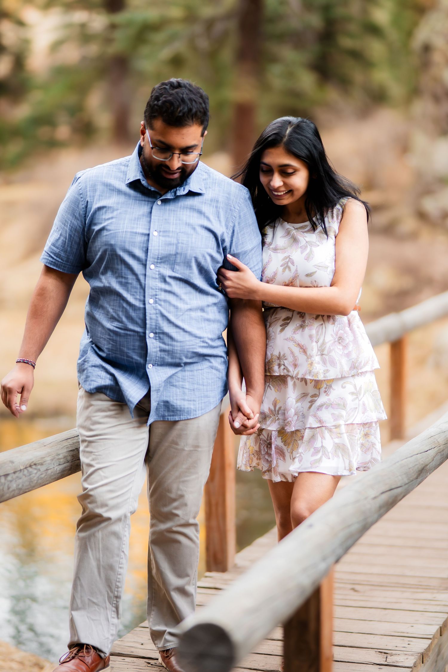 Romantic couple walking together on wooden bridge pathway in nature setting.